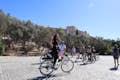 Un gruppo di ciclisti e una ragazza entusiasta in piedi su una eBike sotto la collina dell'Acropoli.