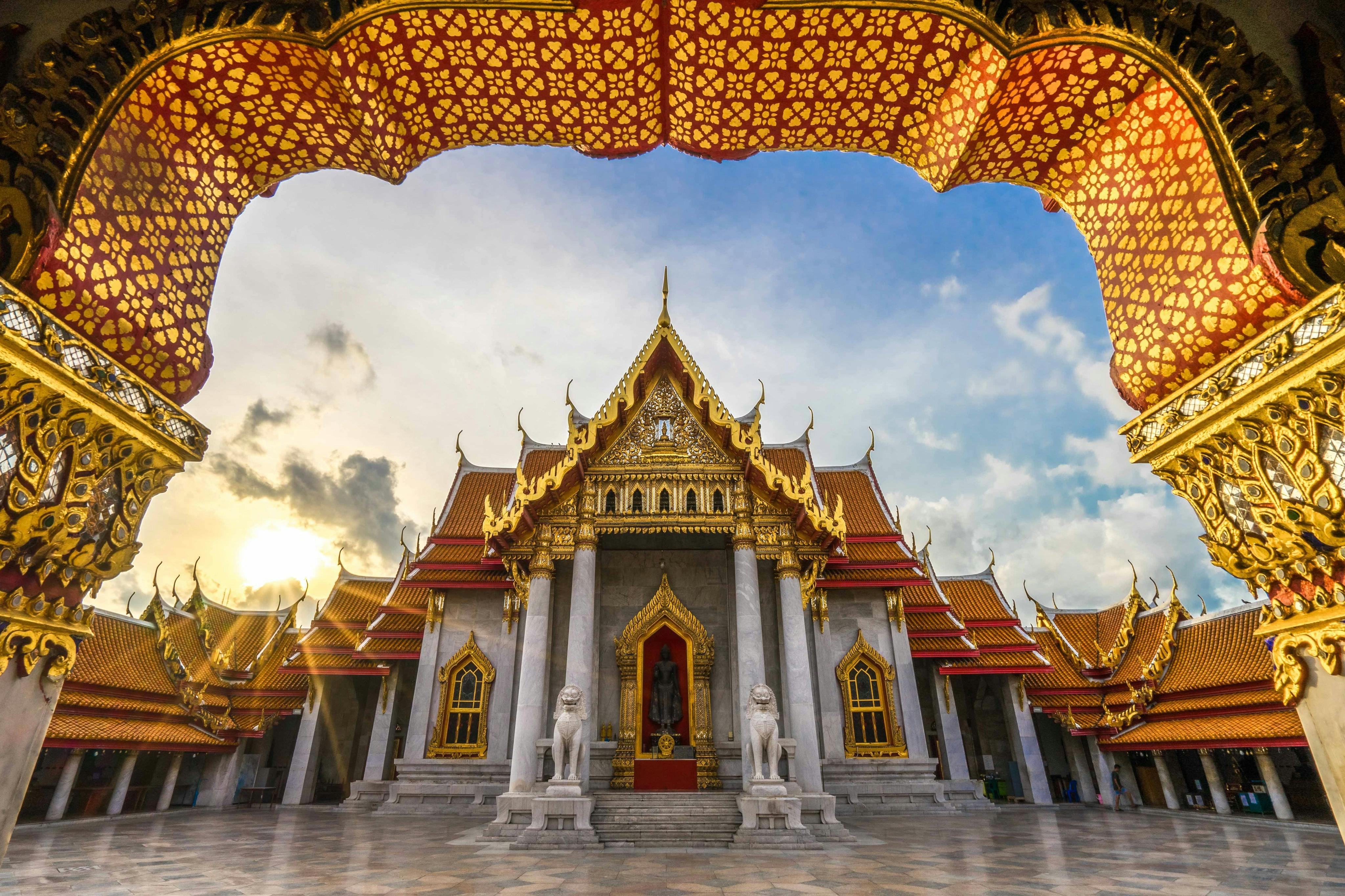 Temple adornat amb sostres vermells i daurats, decoració intrincada i estàtues, situat contra un cel ennuvolat. Terra de marbre en primer pla.