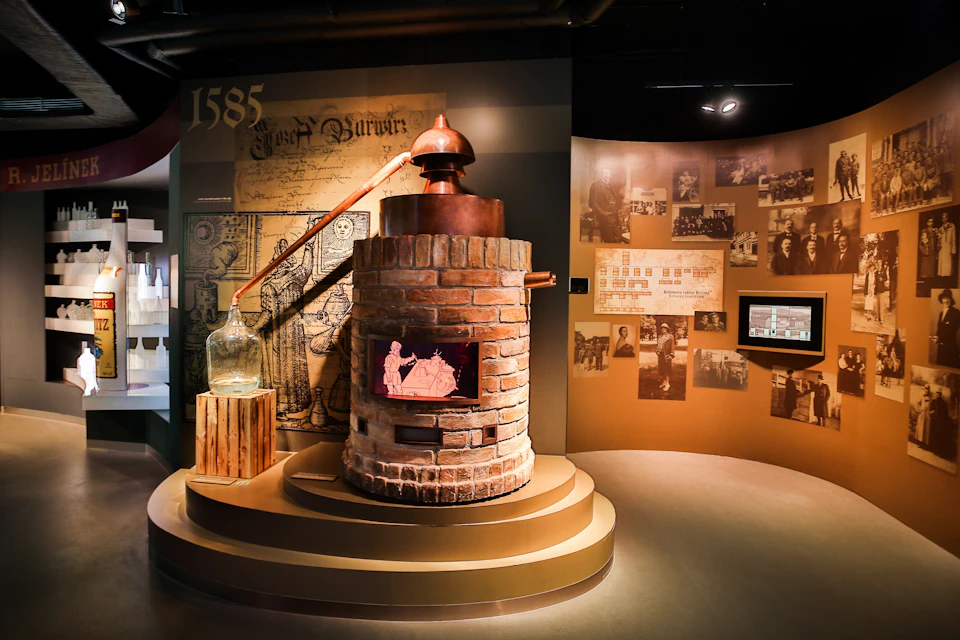A brick still with a copper top is showcased in a museum exhibit featuring historical photographs and old documents.