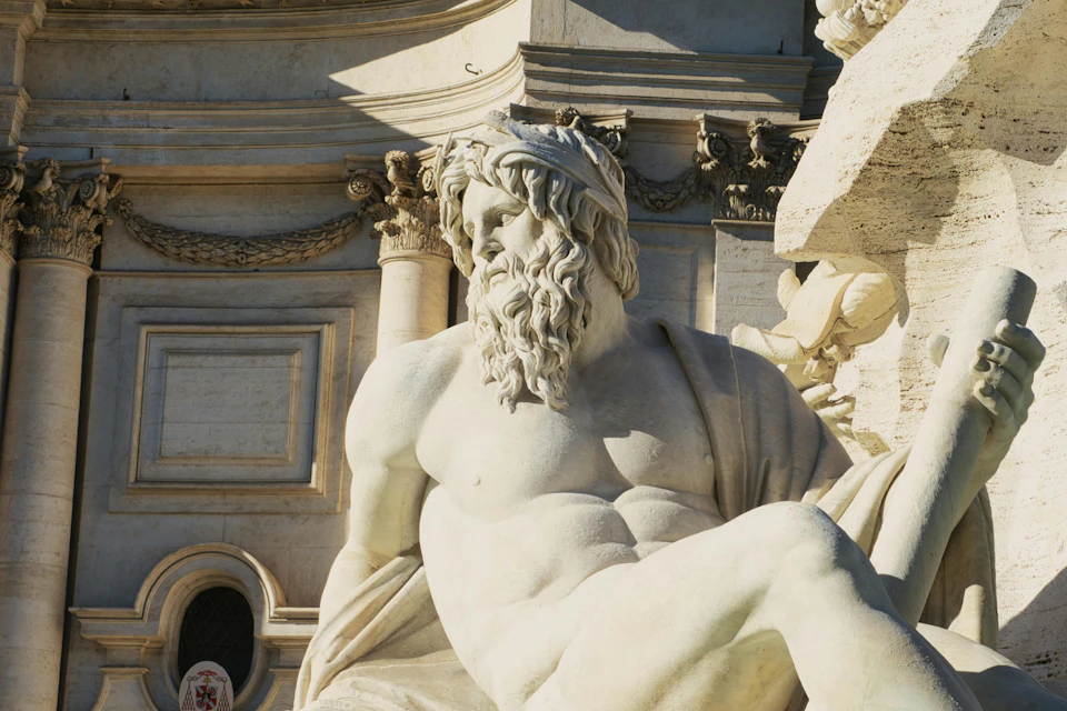 A close-up view of a detailed marble statue of a bearded man with draped fabric, part of a larger ornate architectural structure.