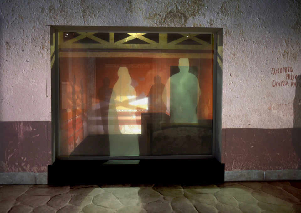 Silhouettes of three people and a horse in a room, with textured walls and a stone floor in the foreground.