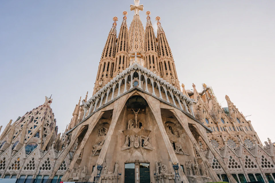 The ornate facade of a large cathedral with tall spires and intricate carvings against a clear sky.