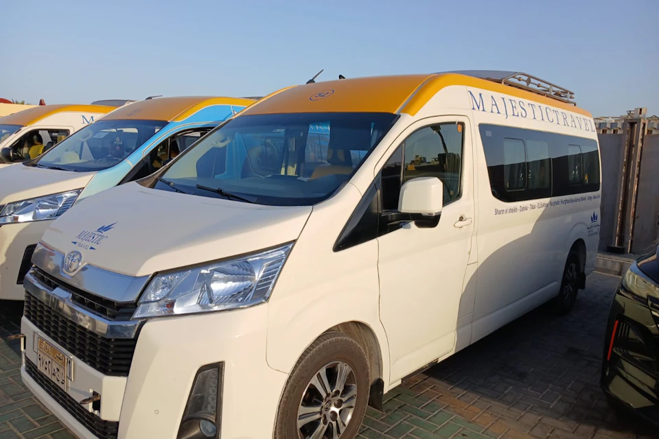 A white van with a yellow roof parked on a paved area, with other similar vans visible in the background.