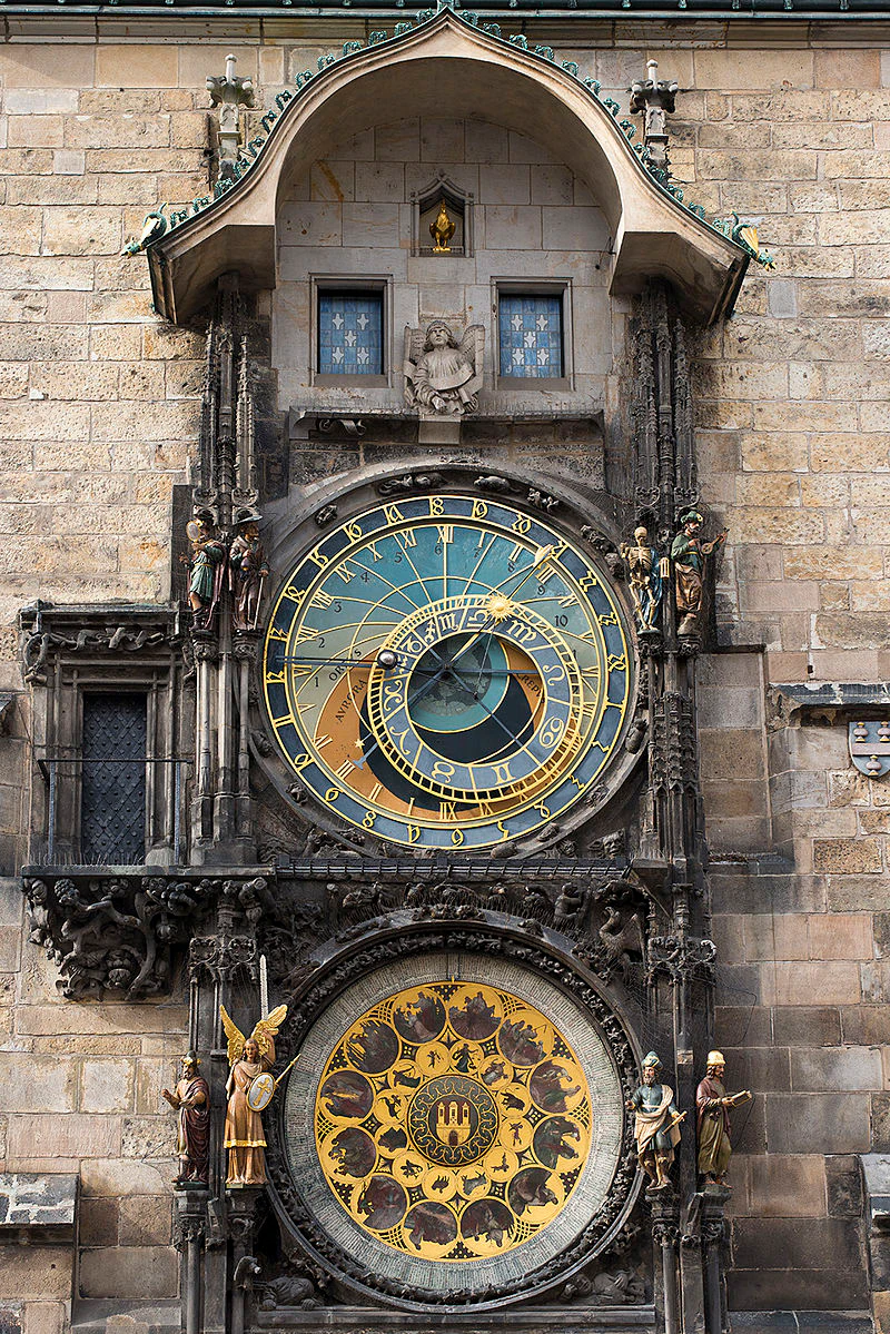 An ornate astronomical clock with multiple detailed dials and figures is mounted on an old stone building.