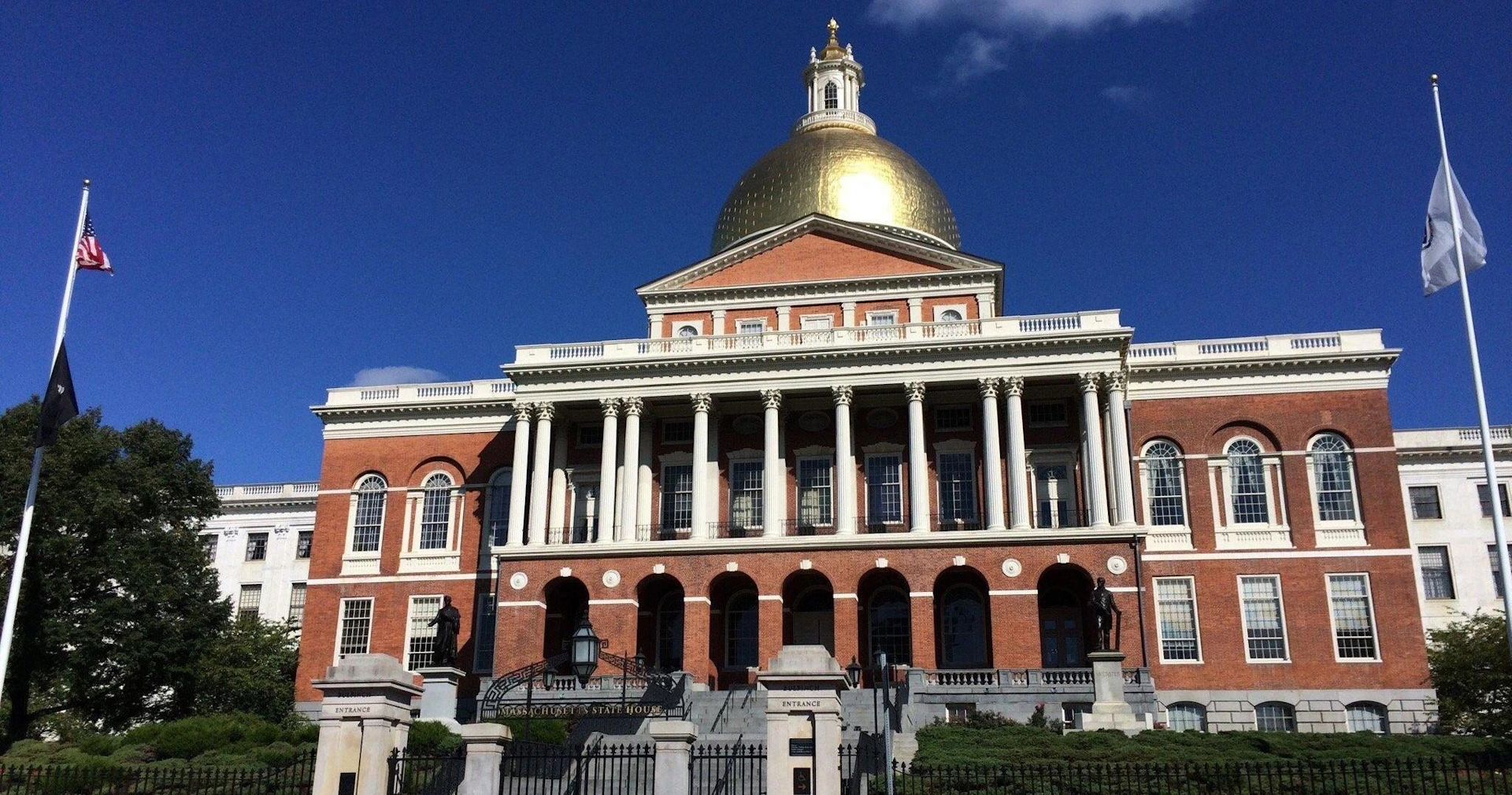A historic building with a golden dome, red brick walls, and white columns under a clear blue sky.