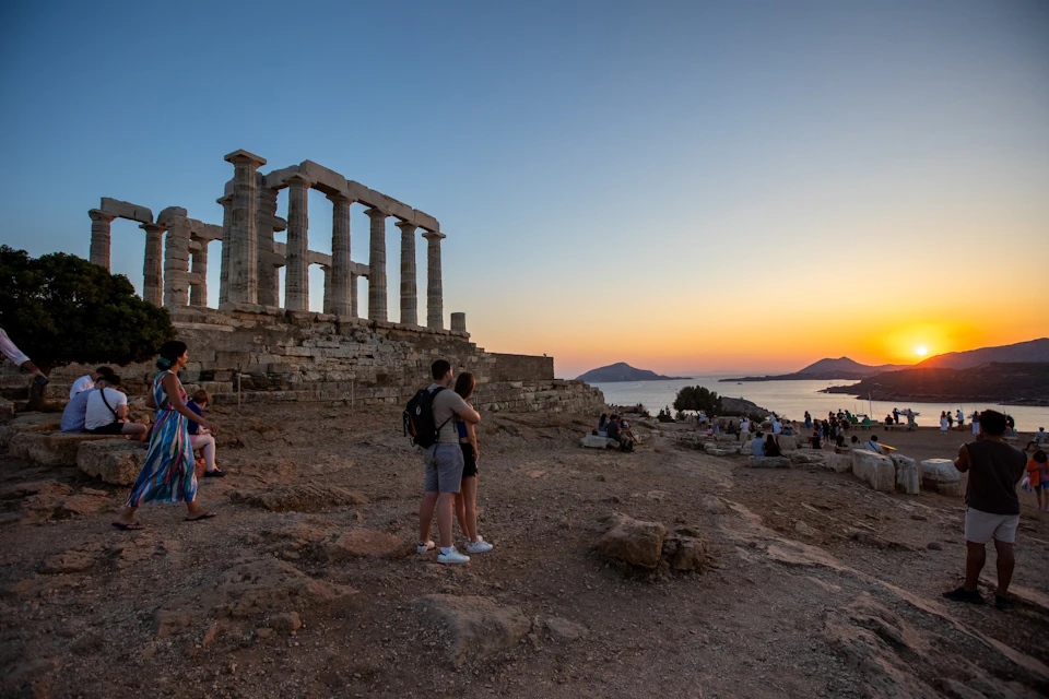 Couples and visitors enjoying the sunset next to the Temple of Poseidon at Cape Sounion.