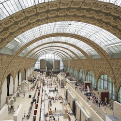 En stor, utsmyckad hall med välvda tak och många människor som tittar på utställningar och skulpturer.