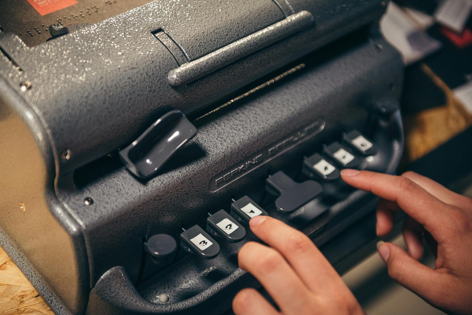 点字を書くために使用されるタイプライタースタイルのデバイスであるパーキンス・ブレイラーでの手のタイピング。