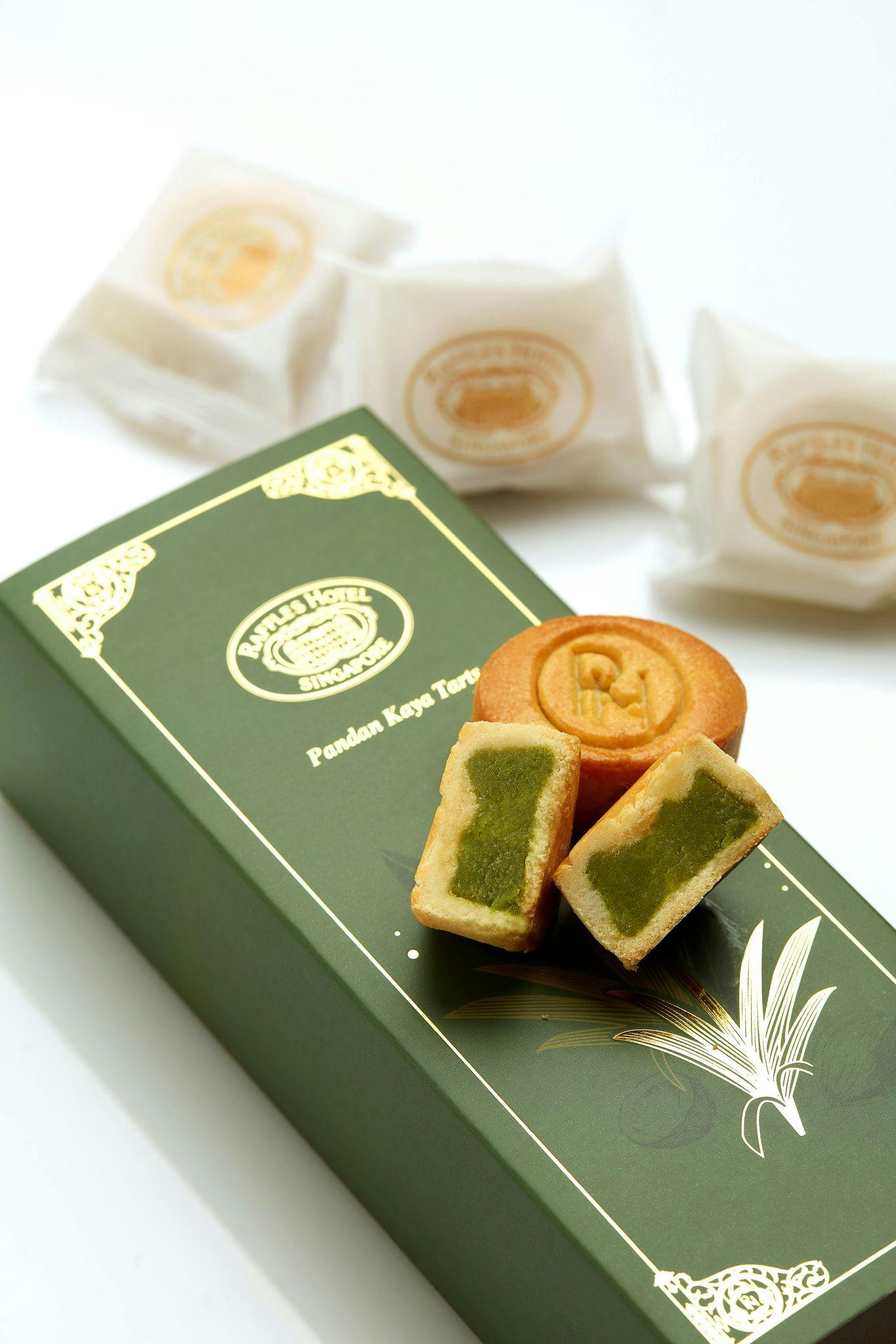 Green box labeled "Raffles Hotel Singapore" containing pandan kaya tarts, with a few tarts and their cross-section displayed.