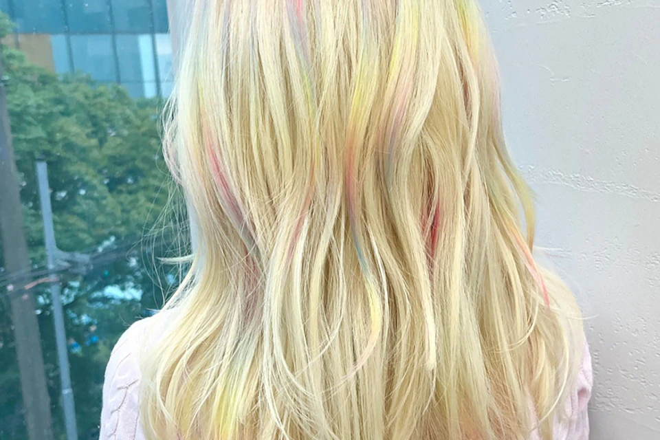 Blonde hair with pastel-colored highlights in shades of pink, blue, and yellow, seen from behind.