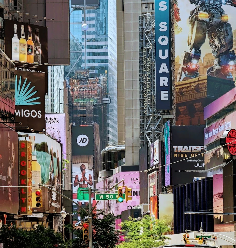 A vibrant street scene in Times Square, with colorful advertisements, billboards, and a visible W 50th Street sign.