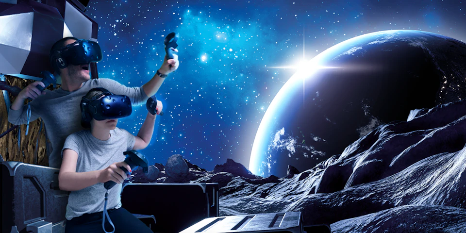 Two people wearing VR headsets and holding controllers, immersed in a space-themed simulation with stars, a planet, and rocky terrain.
