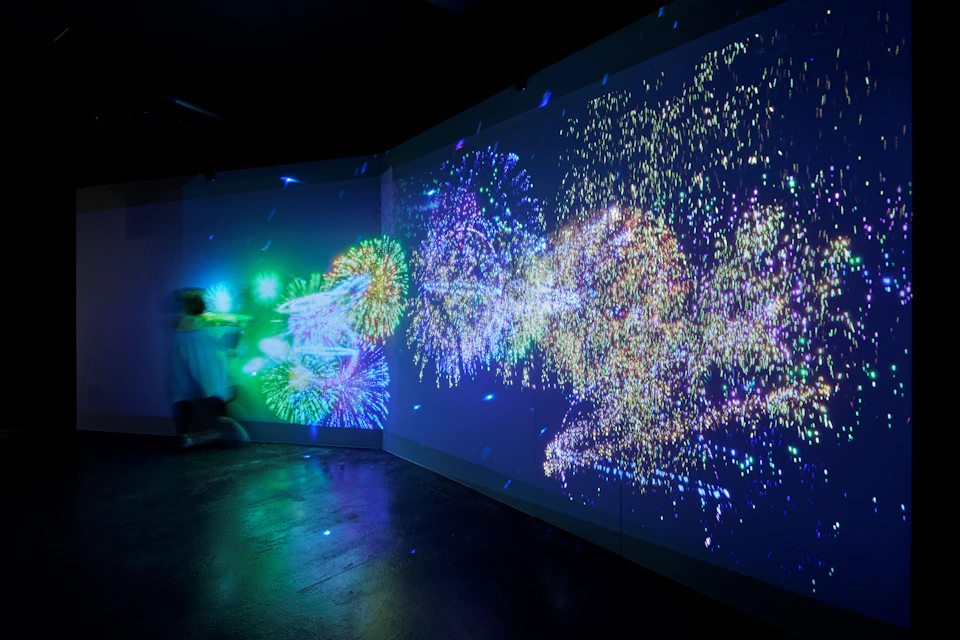 A dark room with colorful, glowing, abstract light patterns projected on the walls.