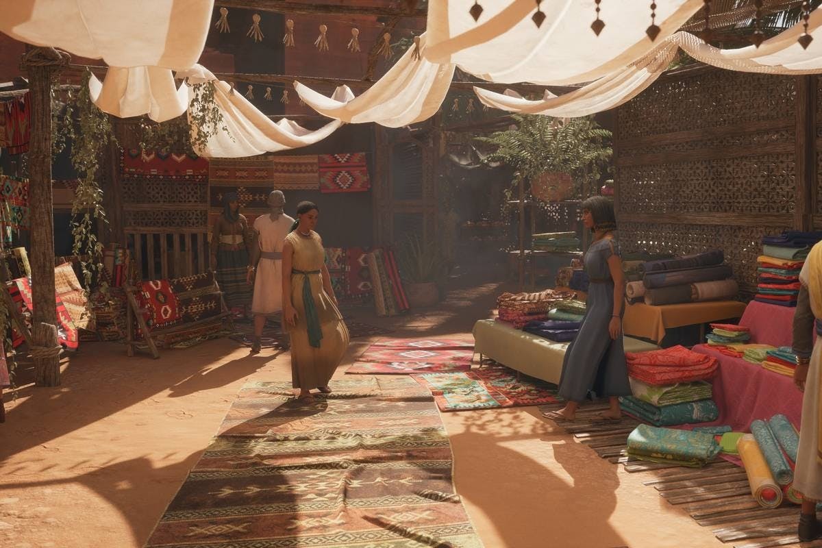 Scena di mercato con persone sotto baldacchini di stoffa. I tappeti sono stesi a terra e i tessuti sono esposti su tavoli bassi.