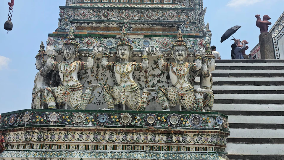 Intricate statues adorned with mosaics on the facade of a temple, with detailed floral and geometric patterns in the background.