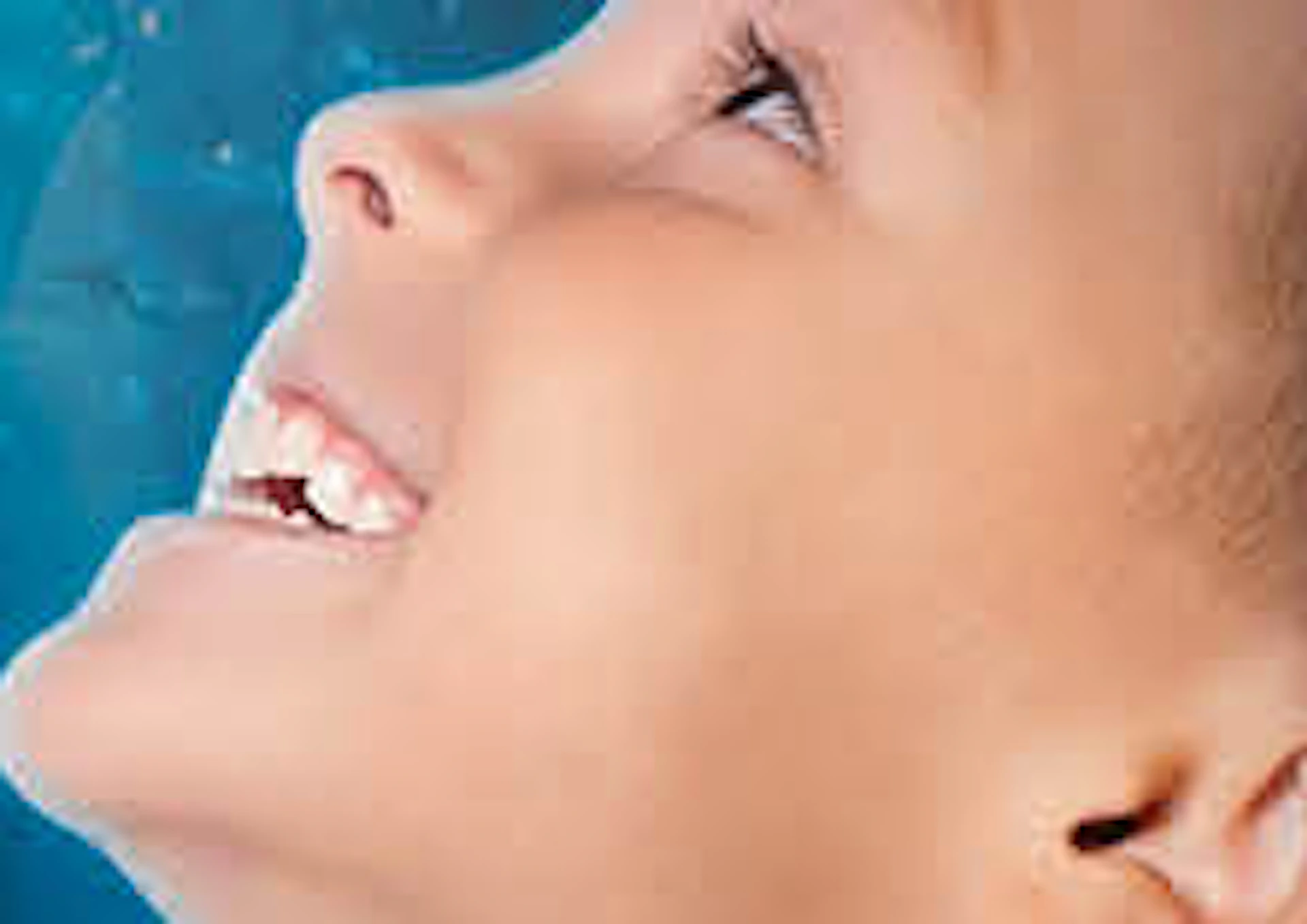 A boy in a plaid shirt smiles and points at penguins swimming underwater in a blue aquarium exhibit.