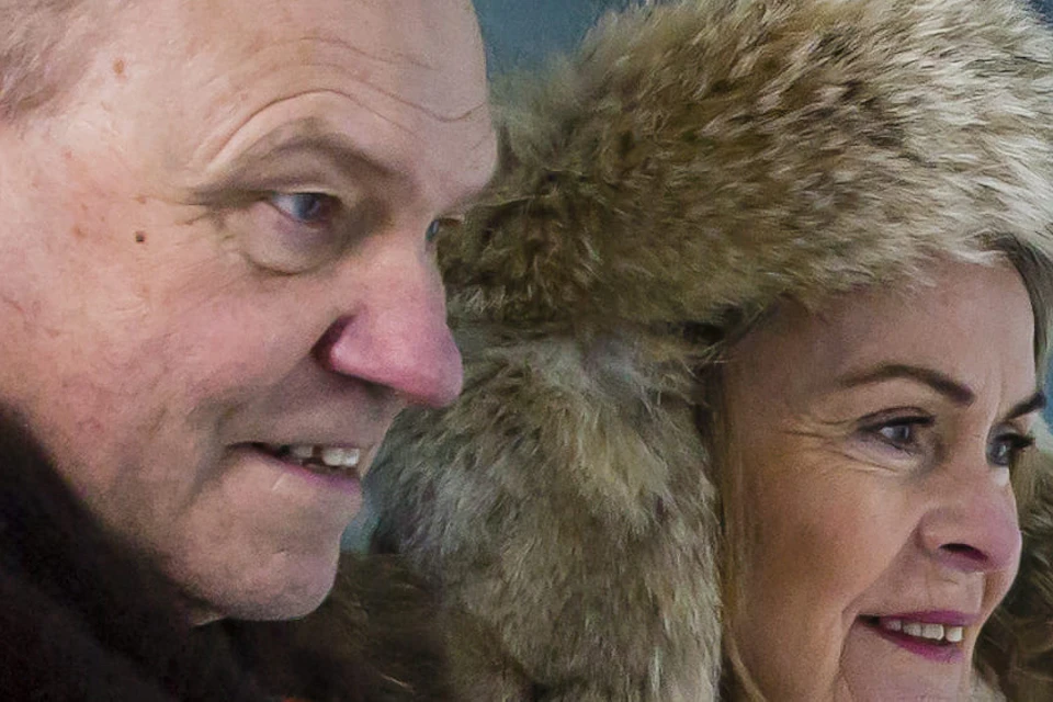 Two people dressed in winter clothing read a sign inside an ice cave. The walls and floor are made of ice.