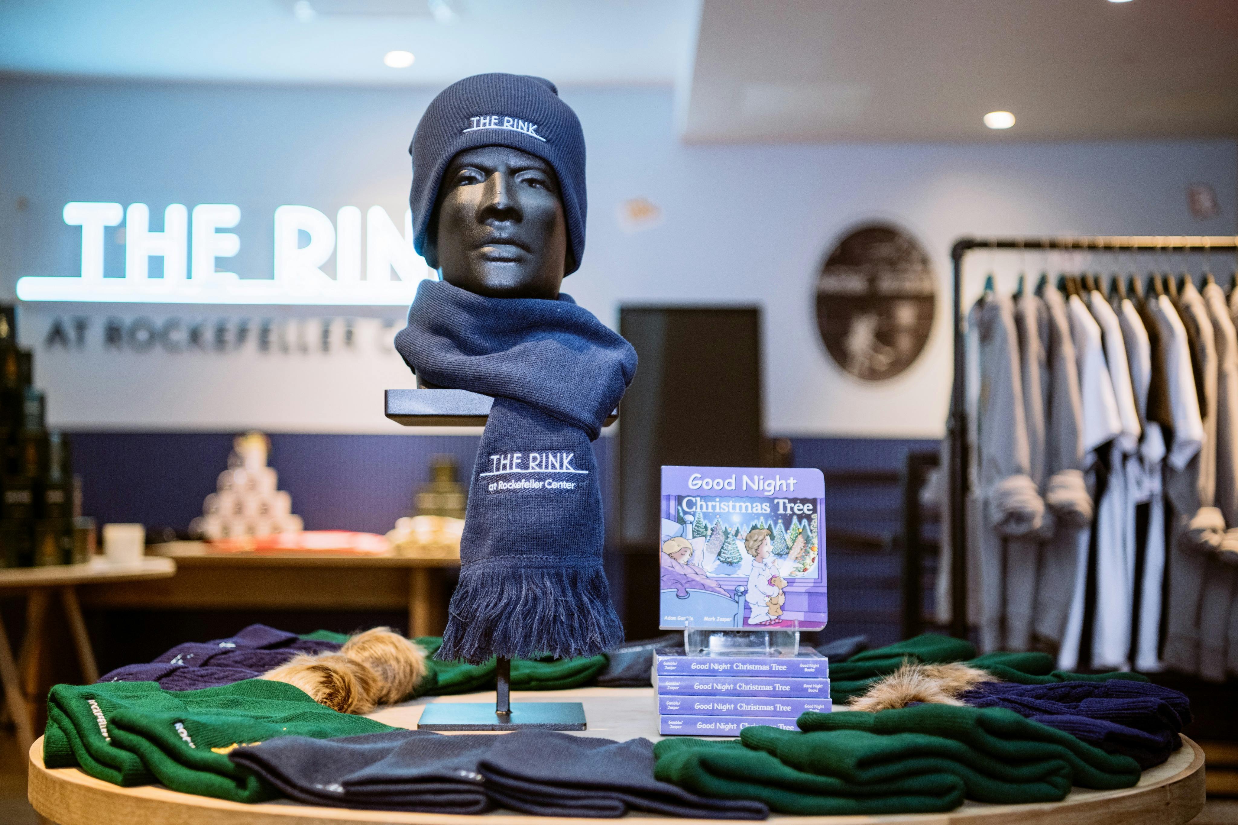"The Rink" 문구가 새겨진 파란색 비니와 스카프를 두른 마네킹 머리. "굿나잇 크리스마스 트리" 라는 제목의 책들이 그 옆에 전시되어 있습니다.