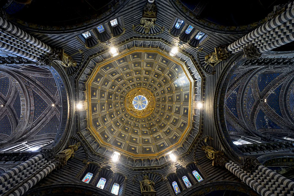 Intricately decorated domed ceiling with ornate gold accents and stained glass windows, viewed from directly below.