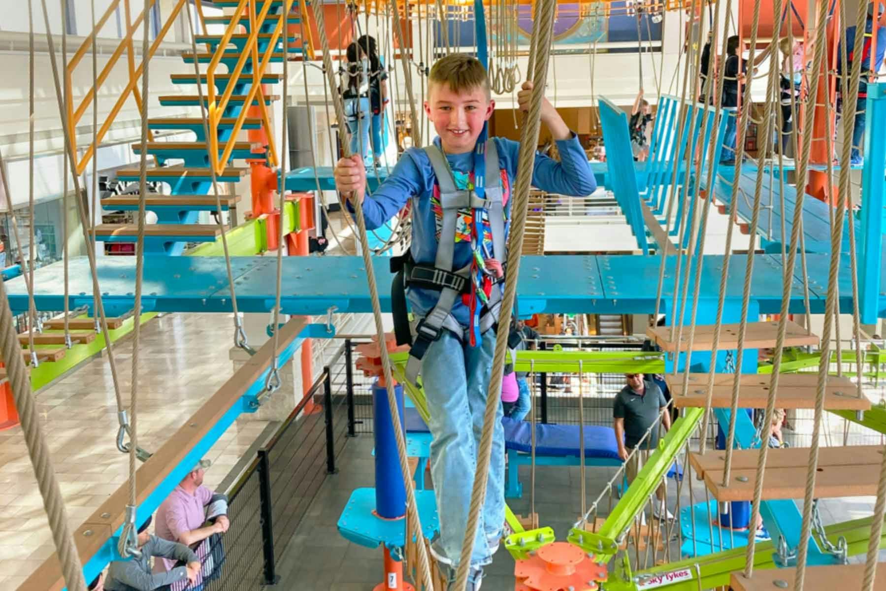 Chłopiec przechodzący przez tor lin przygodowych.