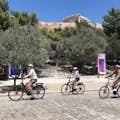 Trois cyclistes utilisant des vélos électriques sous le Parthénon