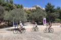 Drie fietsers fietsen met elektrische fietsen onder het Parthenon