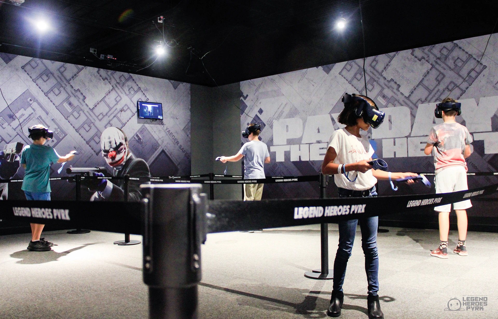 Two people wearing VR headsets in a gaming area with themed decor and barriers, labeled "Legend Heroes PVR."