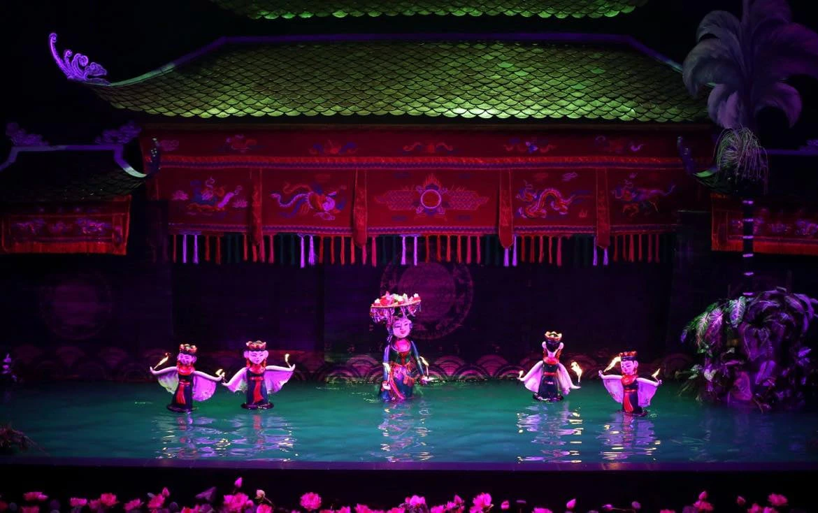 A traditional water puppet performance with colorful puppets on a water stage under a decorated roof.