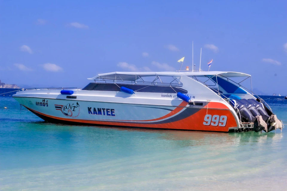 A white and orange speedboat named "Kantee" with the number 999 is docked on clear blue water under a bright sky.