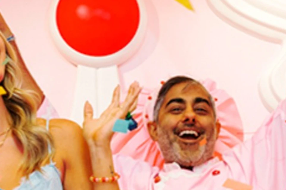 Three people celebrating under falling confetti in a colorful, festive setting.