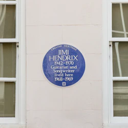 Blå plakett på en vägg lyder: "English Heritage, Jimi Hendrix 1942-1970 Guitarist and Songwriter lived here 1968-1969", mellan två fönster.
