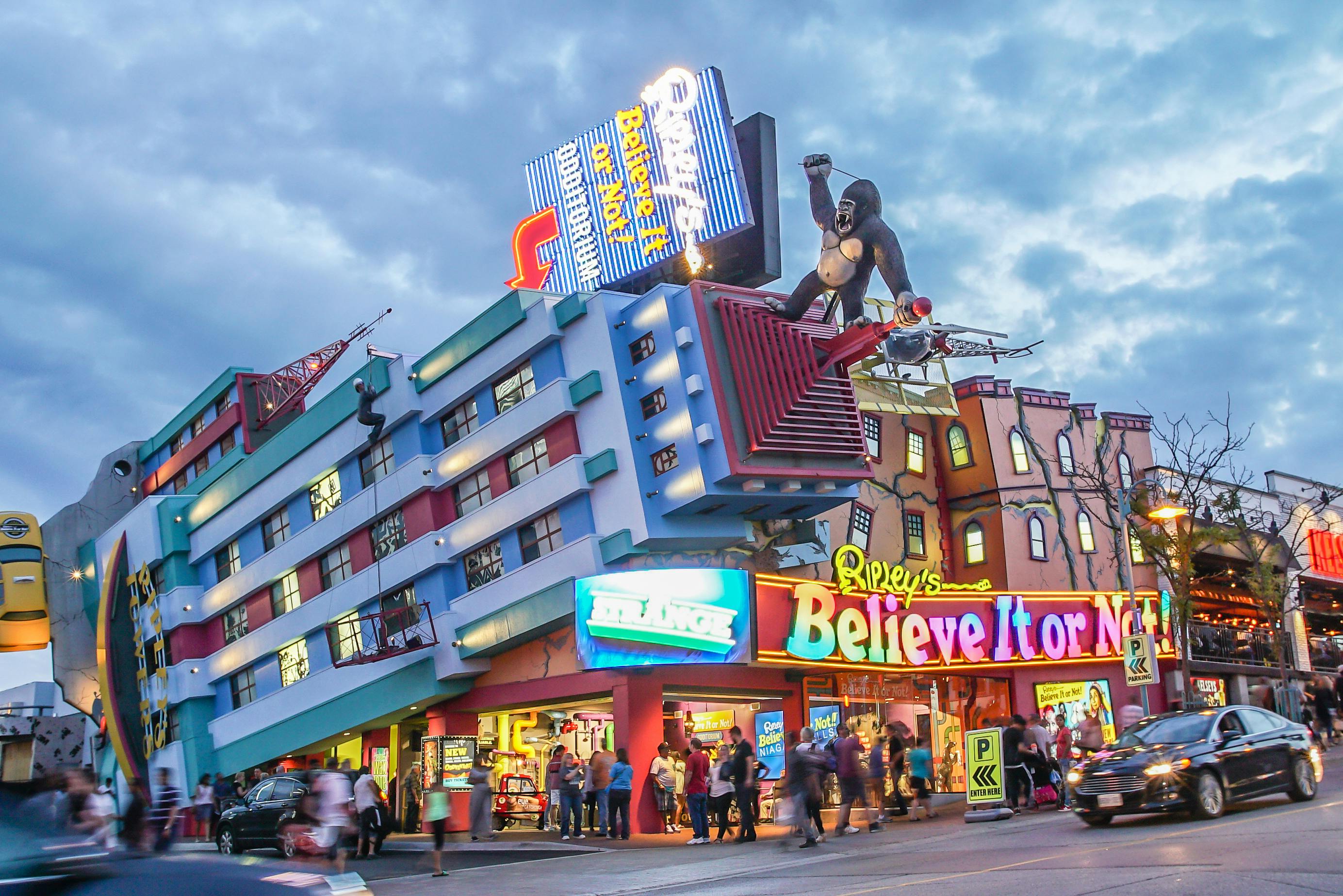 Colorful Ripley's Believe It or Not! museum with a giant gorilla on the roof. People and cars pass by on the street below.