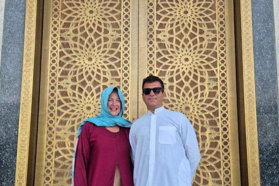 Two people standing in front of an ornate golden door with intricate geometric patterns.