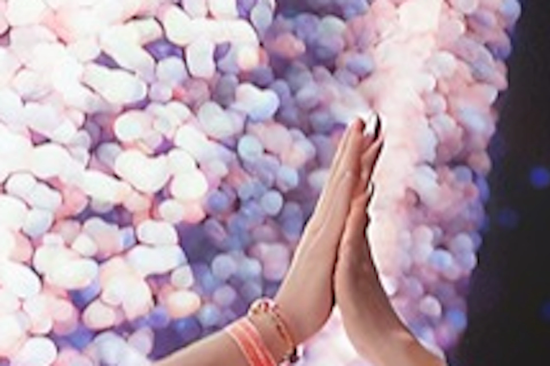 A person in a white shirt giving a high-five to another person against a backdrop of colorful lights.
