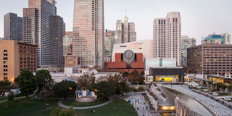 높은 건물이 있는 도시 풍경, 원형의 현대 미술관, 나무와 산책로가 있는 공원.