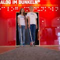 2 meisjes met de lange stok voor de ingang van de Dialoog in het Donker