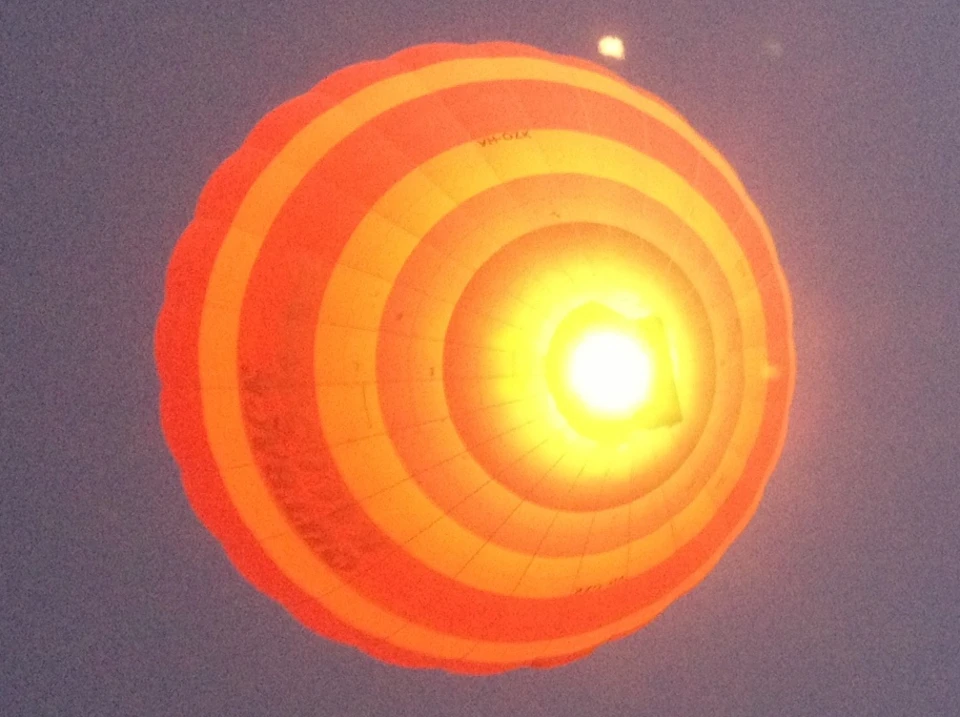 A glowing hot air balloon with red and orange concentric circles against a dusk sky.