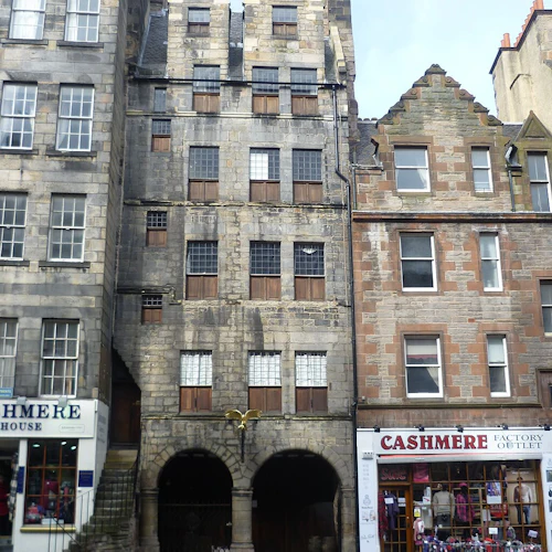 Historisk stenbyggnad med välvda ingångar flankerade av två butiker märkta "Cashmere House" och "Cashmere Factory Outlet".