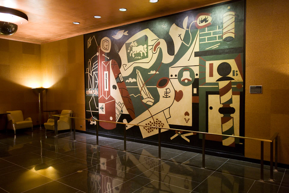 Colorful and abstract mural with geometric shapes and various symbols on a wall in a well-lit, modern interior space.