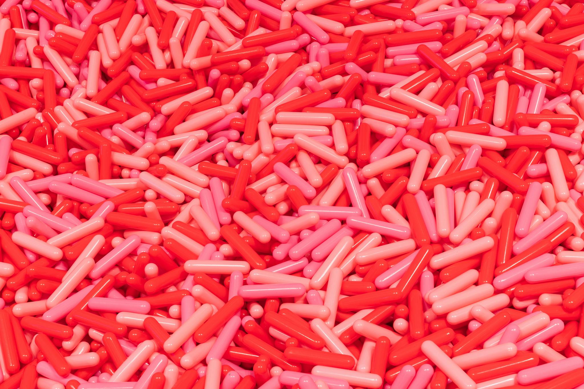 一大堆红色和粉色的胶囊形状的物体密集地堆在一起。