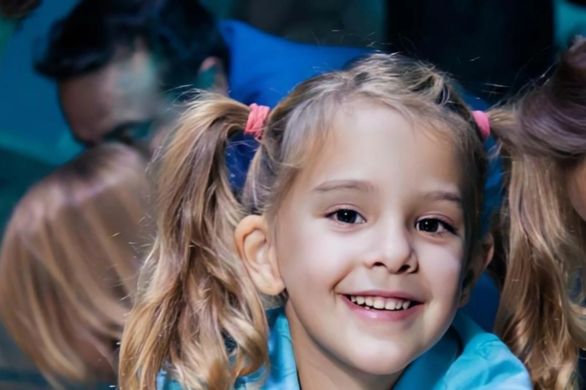Children and an adult interact with marine life in a touch tank at an aquarium, smiling and engaged.