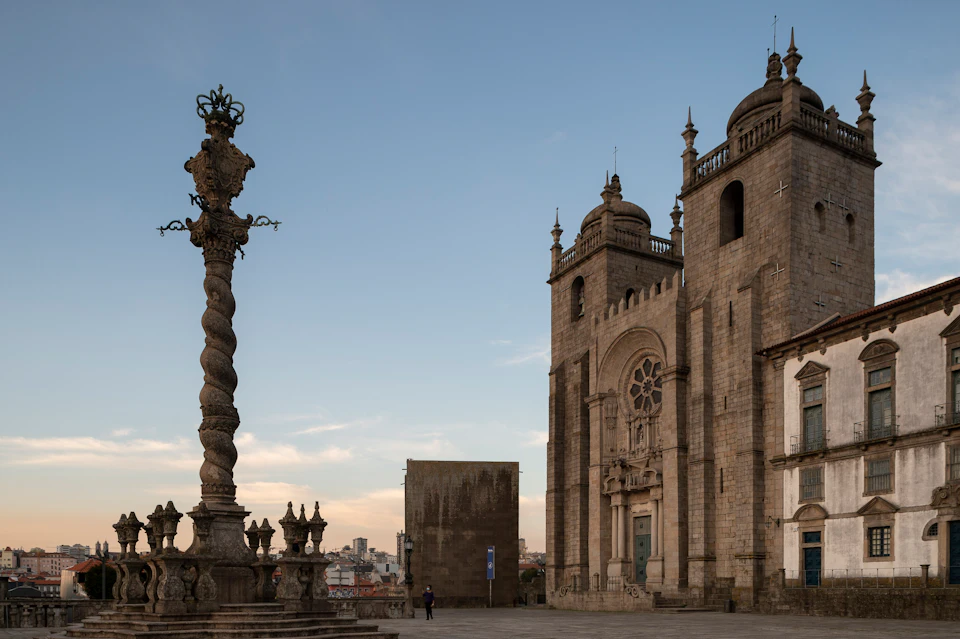Historic stone cathedral with ornate spires, a twisted column, and a small figure in the foreground under a clear sky.