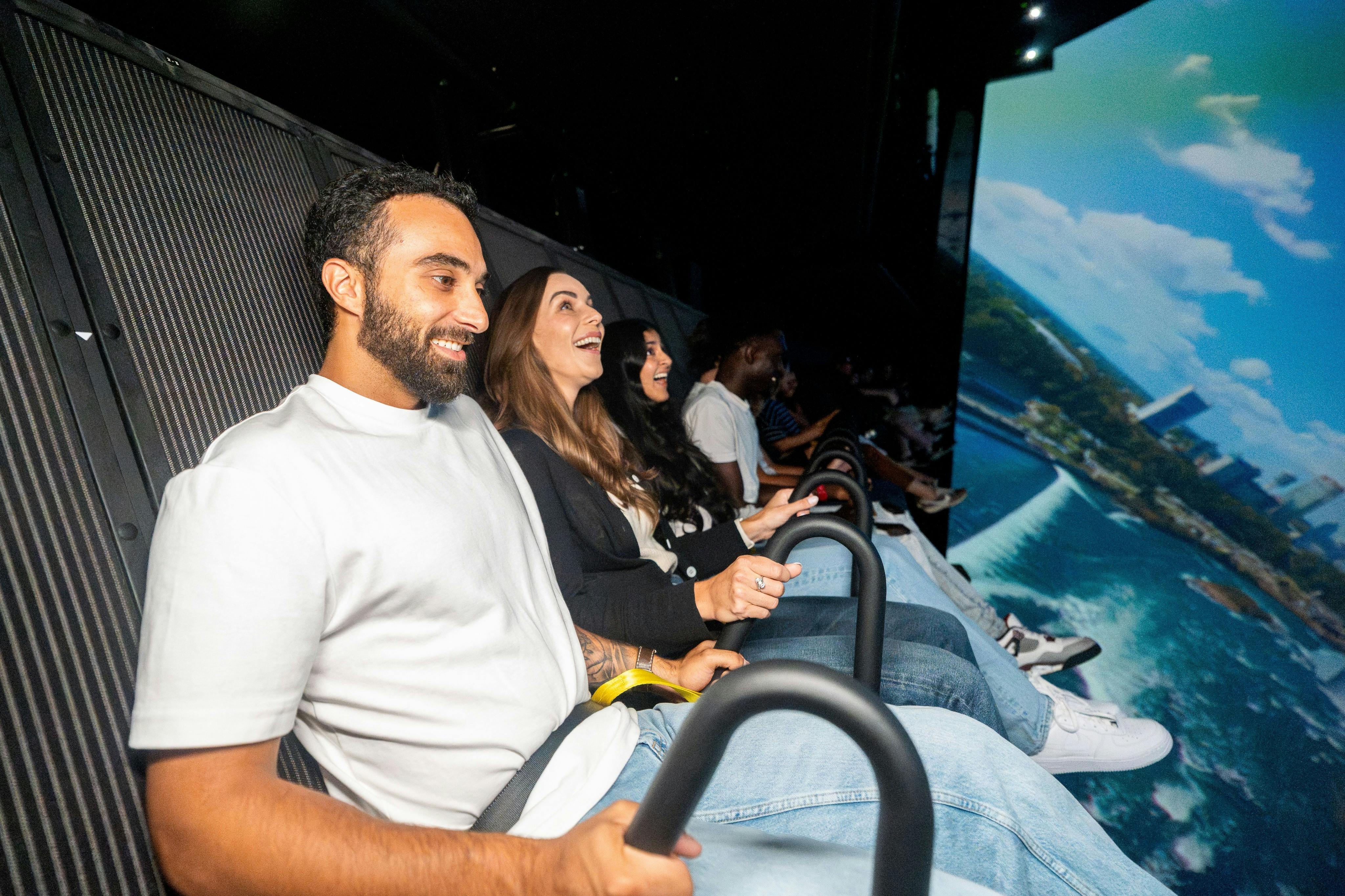 人们坐在剧院座位上，拿着安全栏，微笑着，暗示他们正在乘车或参加互动表演。