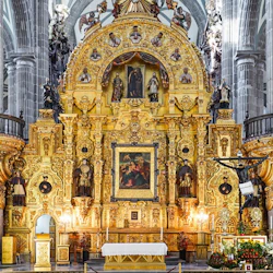 An ornate church altar made of gold with religious statues and paintings, flanked by columns in the background.
