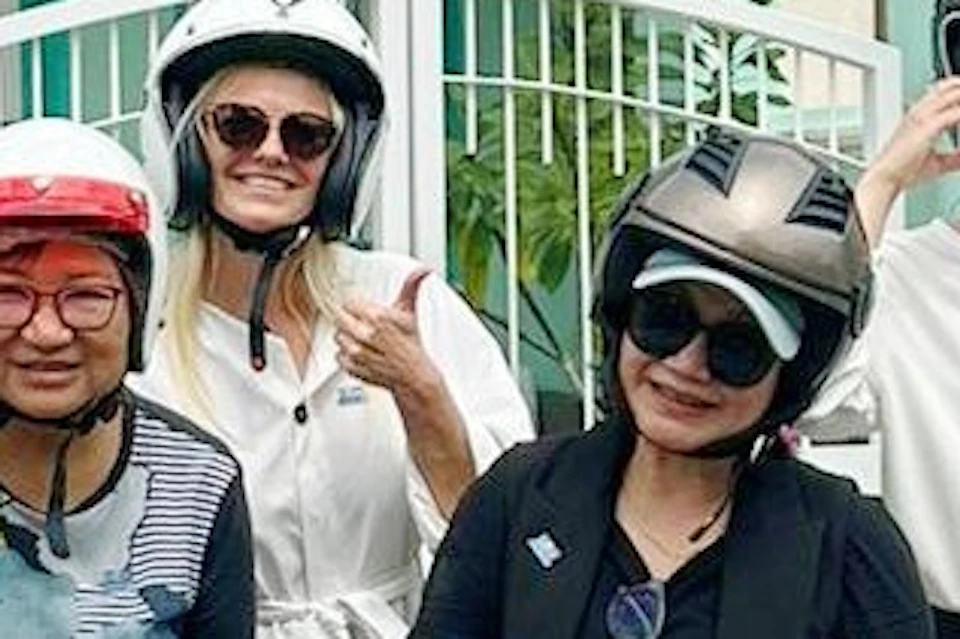 A group of people in helmets posing with scooters in front of colorful buildings with ornate facades.