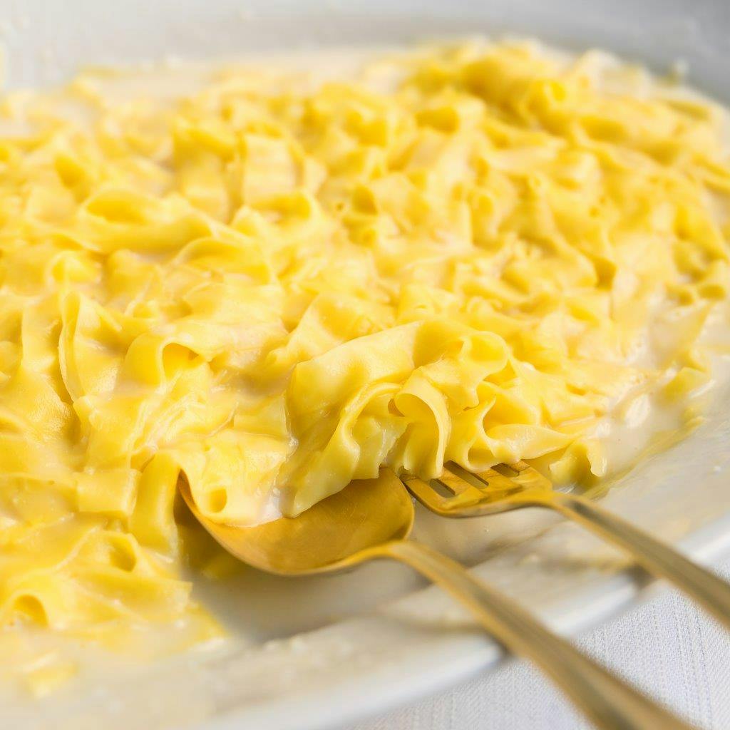 Тарелка кремовой пасты феттучини с двумя золотыми вилками.