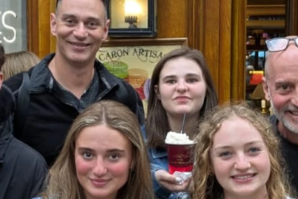 A group of people posing with desserts in front of a café called Carette.