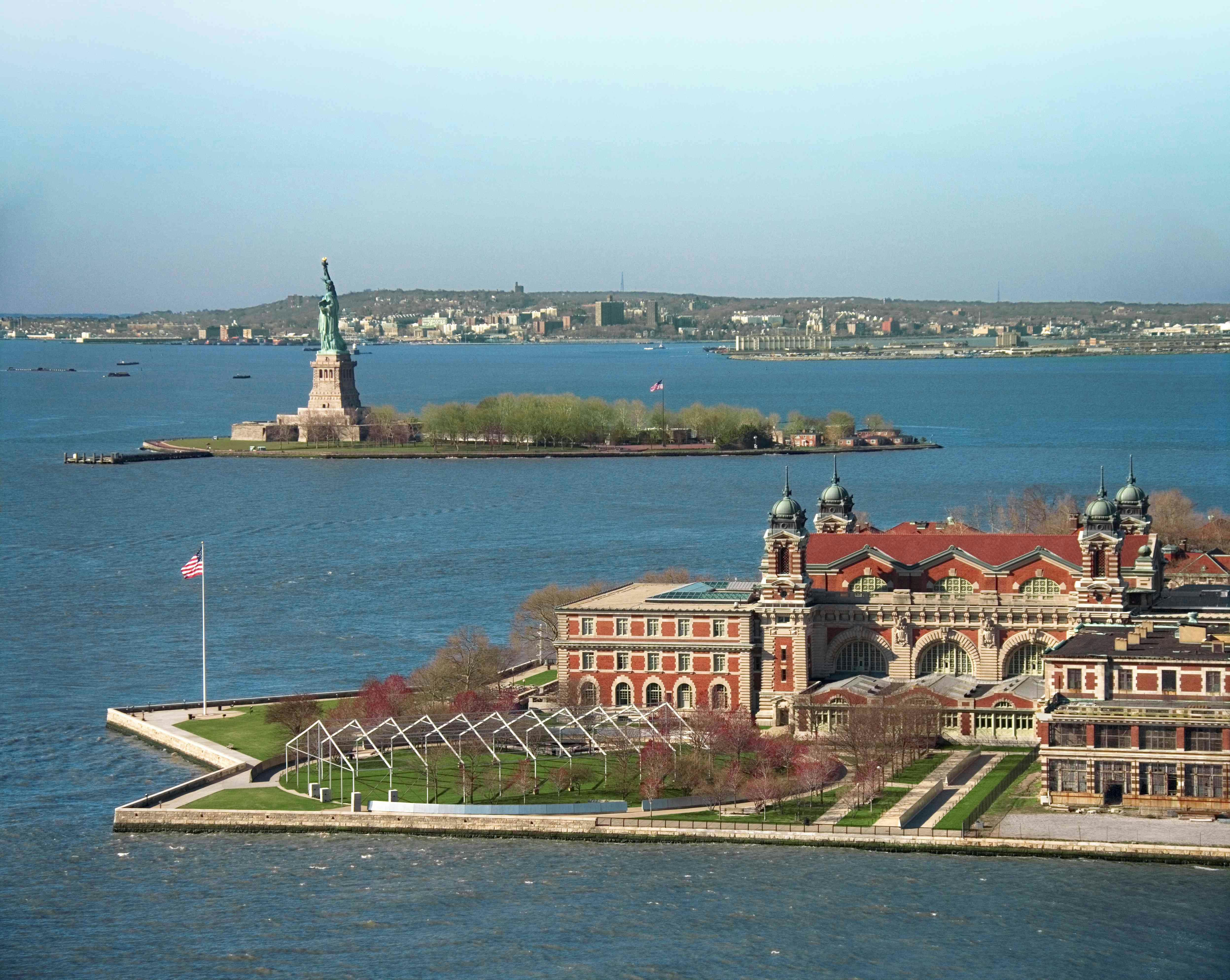 Udsigt til Frihedsgudinden og Ellis Island med bygninger og vand i forgrunden.