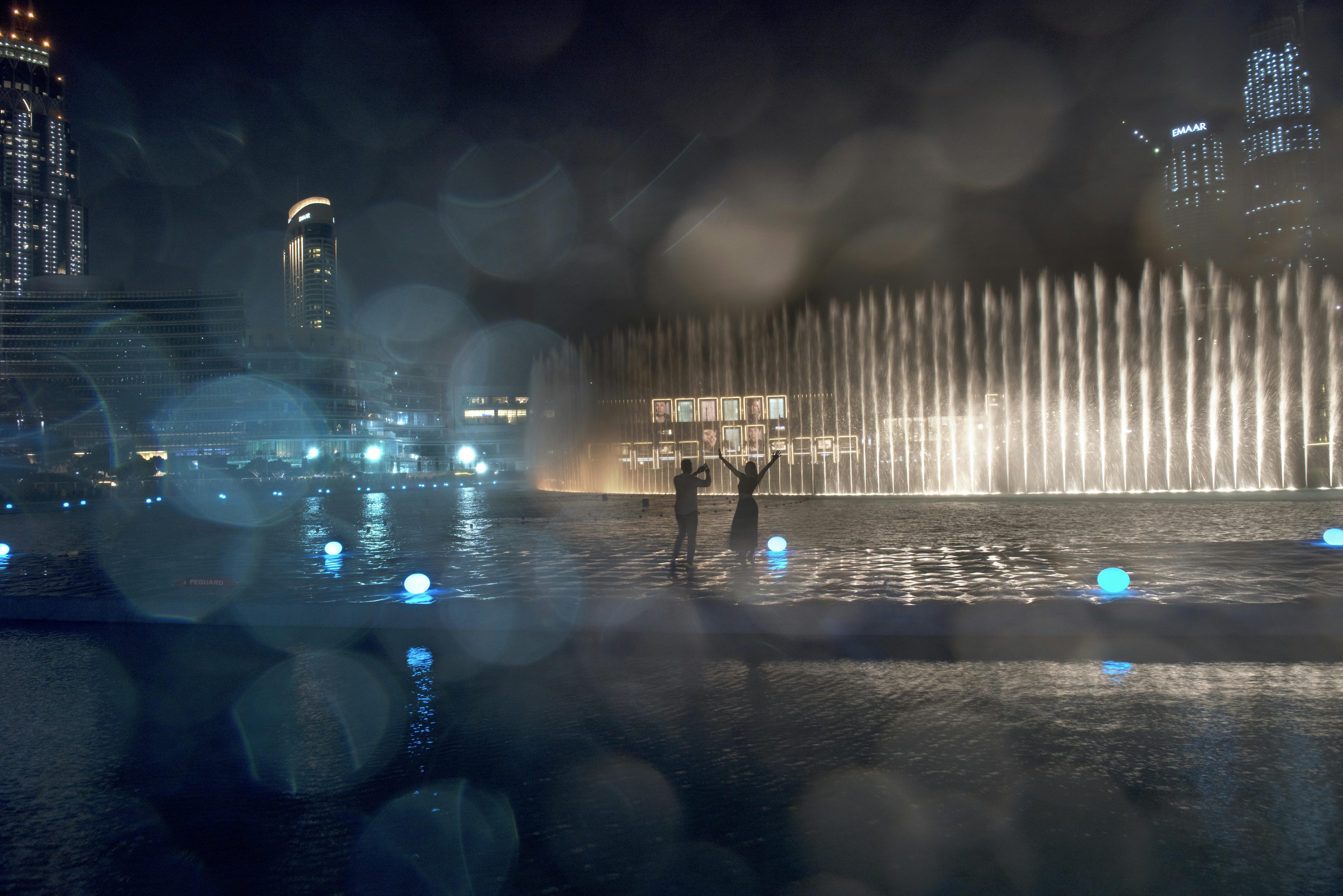 Afbeelding van een stel op de promenade dat naar de Dubai Fountain-show kijkt
