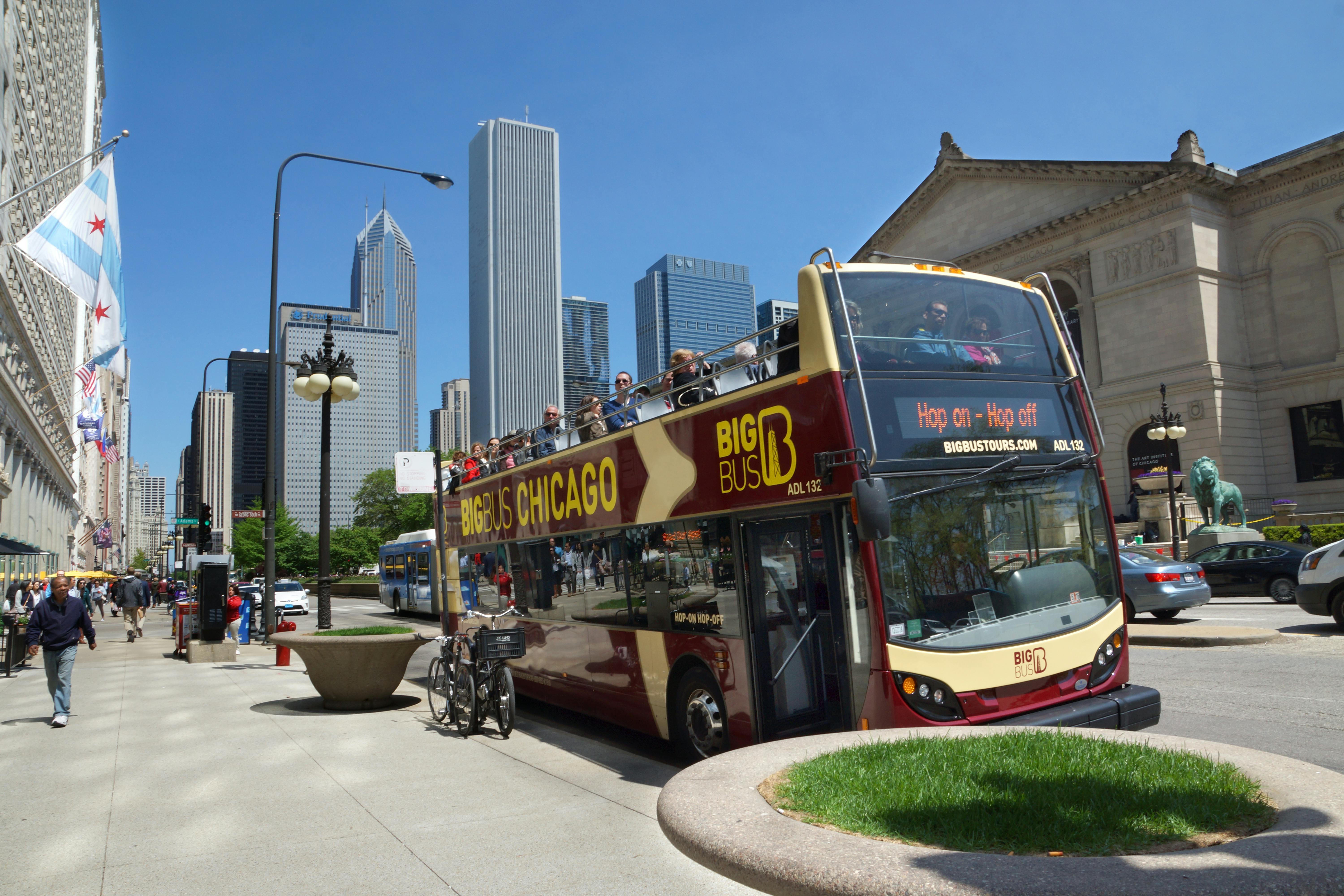 Els turistes viatgen en un "Big Bus Chicago" de dos pisos a prop de l'Institut d'Art de Chicago, amb gratacels visibles al fons.